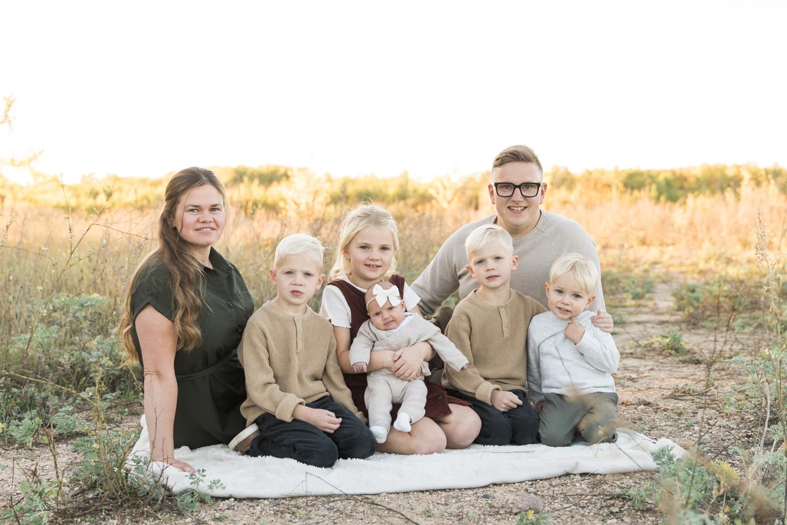 Stefan Hodelmann with his family, sitting on a blanket in a prairie field at sunset